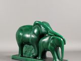 une image représentant une statue d'éléphant verte sur laquelle est perché un éléphanteau