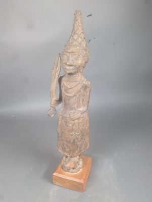 statue représentant une personne portant un chapeau orné d'une plume, posée sur un socle en bois