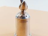 a small silver bell with a bird on top of it