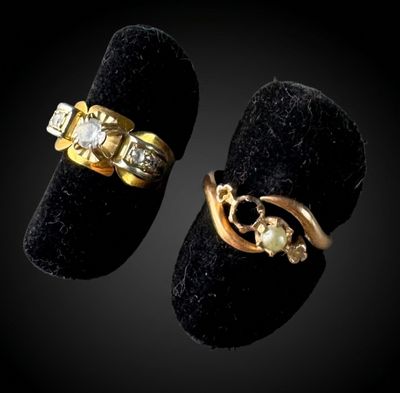 two gold rings with diamonds and a pearl on a black velvet ring holder