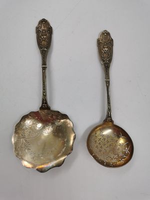 deux cuillères en argent ornées de motifs élaborés, posées l'une à côté de l'autre