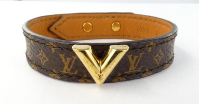 a close up of a brown leather bracelet with a gold v on it