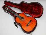 une image représentant une guitare dans son étui, posée sur une surface blanche