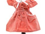 une poupée vêtue d'une robe rouge, posée sur un socle noir