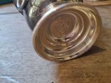 a silver cup sitting on a table next to a teapot