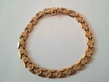 gros plan d'un bracelet en or sur une surface blanche