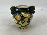 a small vase with lemons on it sitting on a table