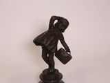 figurine en bronze représentant un homme portant un seau et un sac