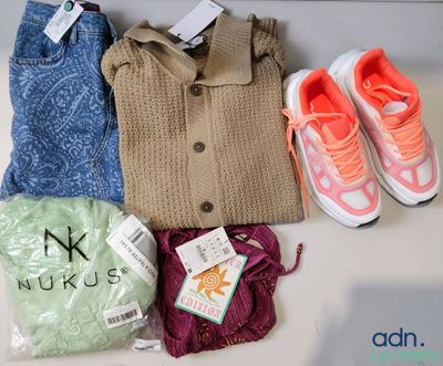 Plusieurs paires de chaussures, un pull, un jean, une paire de baskets et un sac de vêtements sont posés sur une table.