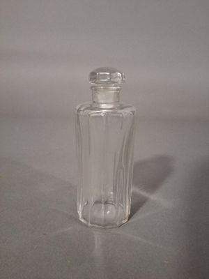 une petite bouteille en verre avec un couvercle transparent posée sur une table