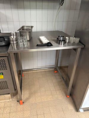 une table en acier inoxydable sur laquelle sont posés des casseroles et des poêles