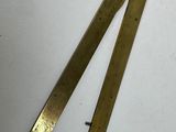 pair of brass plated brass rulers on a white surface