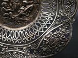 a silver plate with a design on it on a black background