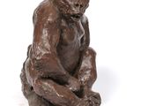 bronze sculpture of a monkey sitting on a white surface