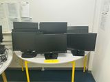 a lot of computer monitors on a table in a room