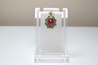 boucles d'oreilles vertes, rouges et dorées présentées dans un présentoir en acrylique transparent