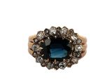 gros plan d'une bague avec une pierre bleue entourée de diamants