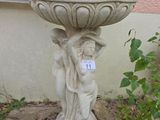 une statue représentant une femme tenant un bassin à oiseaux dans un jardin