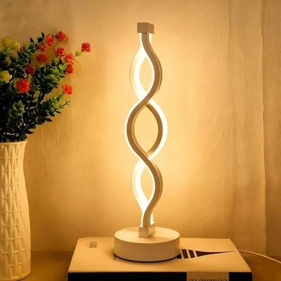 une lampe posée sur une table à côté d'un vase de fleurs