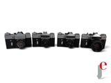 four old cameras are lined up in a row on a white surface