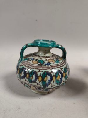 deux vases munis d'anses sont posés sur une surface blanche