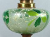 a green glass vase with a gold lid on a wooden stand