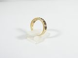 an image of a gold ring with black diamonds on a white surface