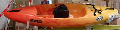 Des kayaks aux couleurs vives sont suspendus à un support dans un entrepôt