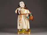 figurine of a monk holding a basket and a bottle