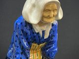 une figurine représentant une vieille femme assise sur un tabouret