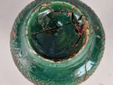 a close up of a green vase with a hole in it