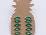 a close up of a pair of green earrings on a cardboard board