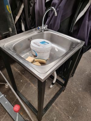 a metal sink with a bucket on it in a room