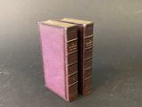 two pink books sitting on top of a table next to each other