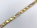 gros plan d'un bracelet en or sur une surface blanche