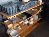 une étagère sur laquelle sont posés de la vaisselle et des tasses, dans une cuisine
