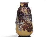 un vase jaune orné de fleurs violettes sur fond blanc