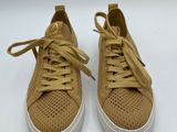 a pair of tan sneakers with white soles on a white surface