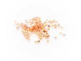 a pile of gold colored glass beads on a white background