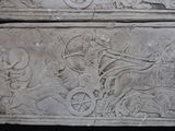a stone carving of a man on a horse drawn carriage