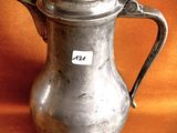 a silver pitcher with a tag on it sitting on a table