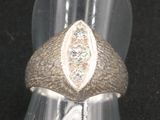 une bague en argent sertie d'un diamant, posée sur une surface noire