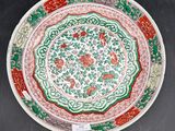 a close up of a red and green plate with flowers on it
