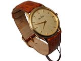 a gold watch with a brown leather band
