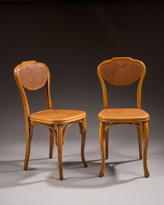two wooden chairs with wicker seats on a grey background