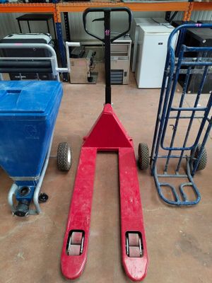 a red fork lifter sitting on the floor next to a blue hand truck