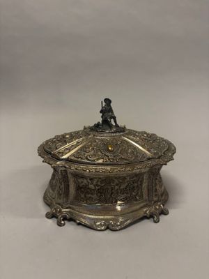 une boîte plaquée argent sur laquelle est assis un homme