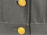 the back of a gray dress with yellow buttons on it