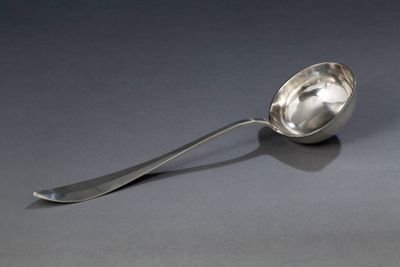 une cuillère en argent avec un manche de cuillère sur une surface grise