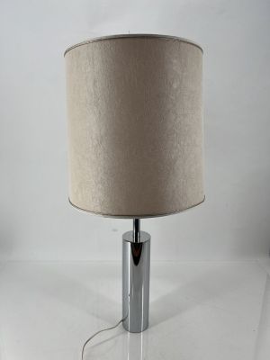 a chrome table lamp with a beige shade on top of it